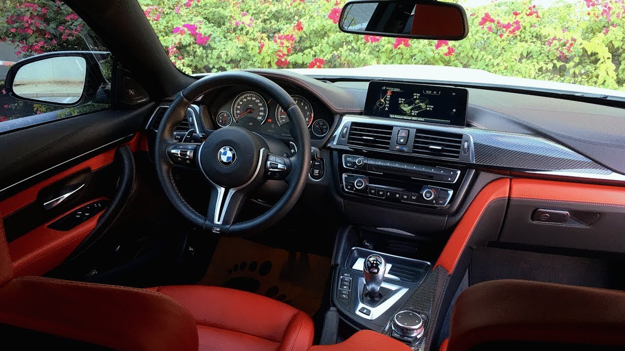 Interior shot of a BMW M4 F82 showing the M steering wheel, sport seats, and driver-focused cockpit
