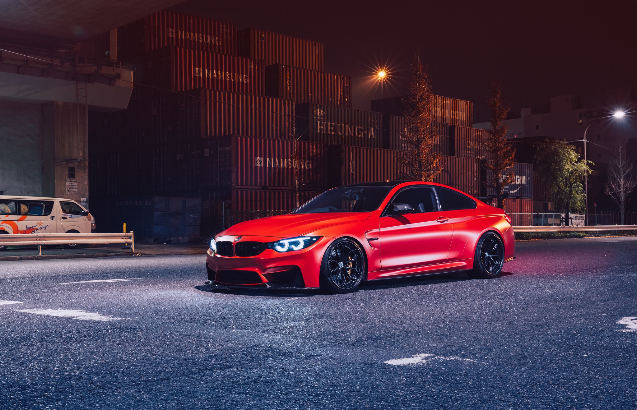 BMW M4 F82 photographed at night under neon city lights with an aggressive stance
