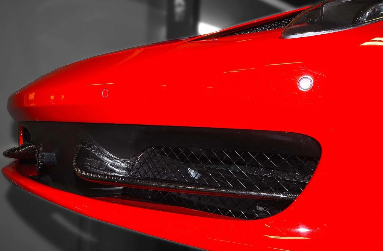 Close-up front bumper detail of a Ferrari 458 Italia highlighting the small front aero winglets and splitter area