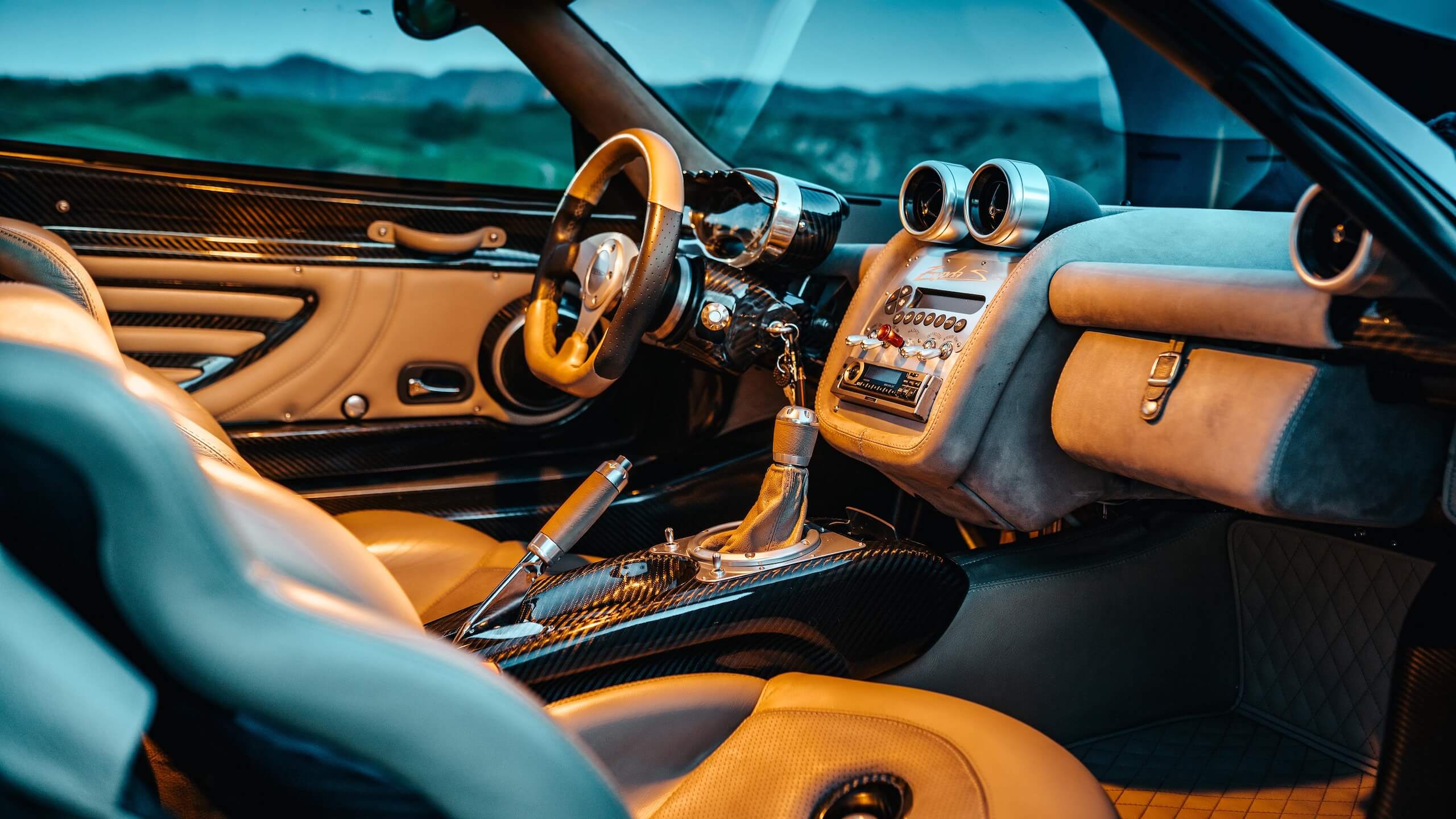 Close-up of a Pagani Zonda interior showing exposed carbon fiber, machined metal switchgear, and analog gauges